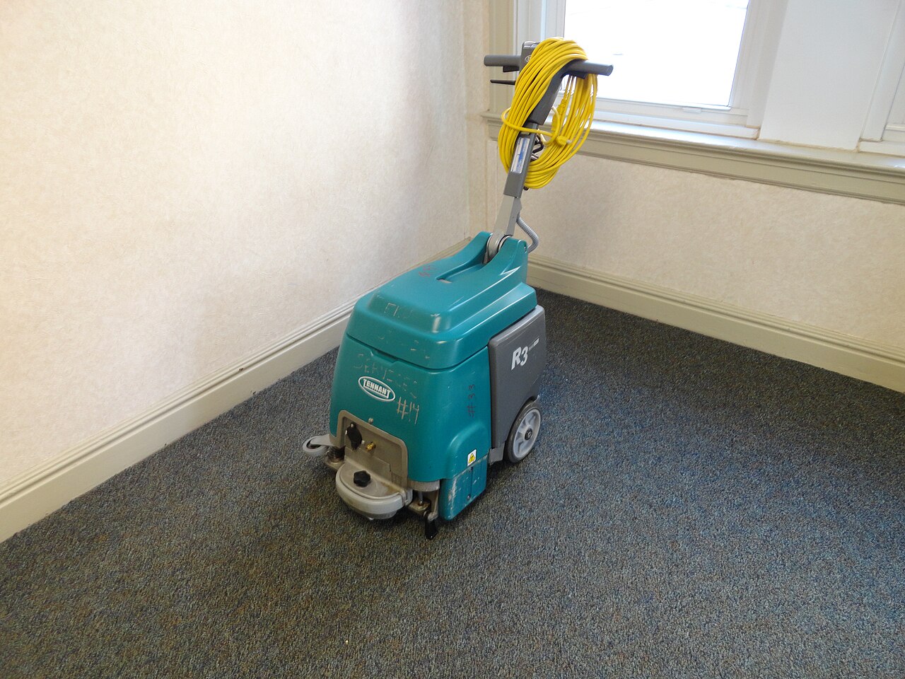 Professional carpet cleaning machine standing in a carpeted room