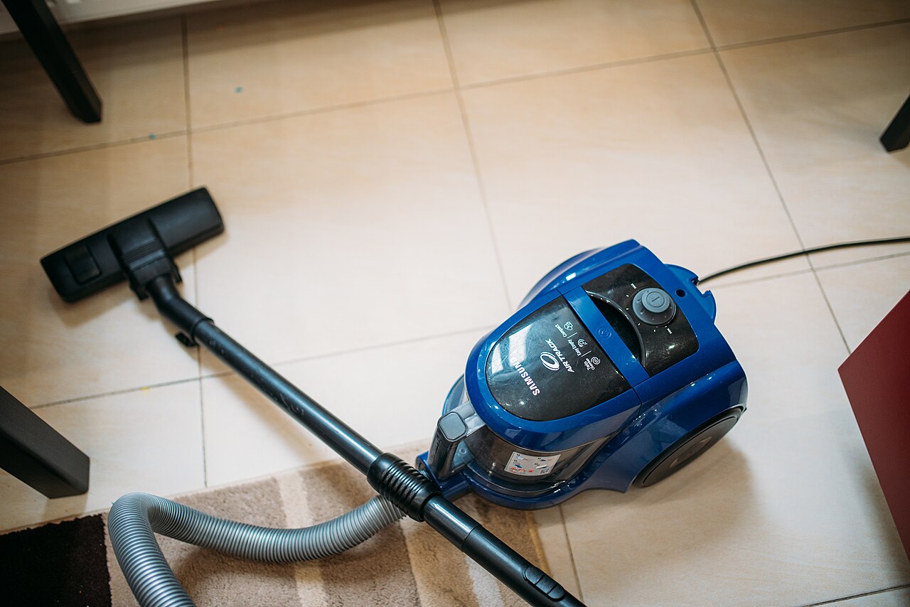 Canister vacuum cleaner ready for work on a tiled floor