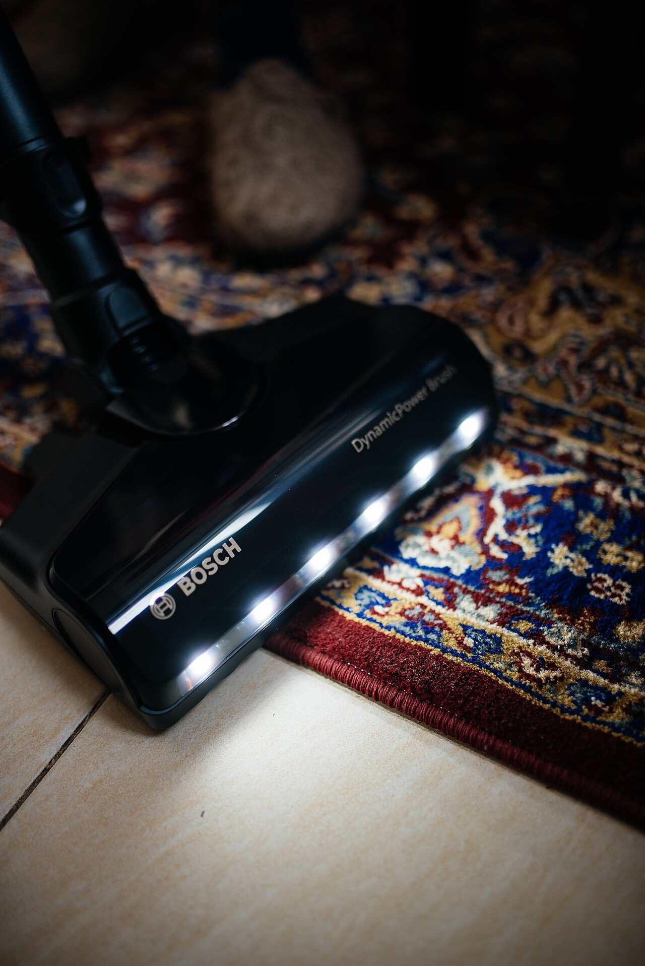 Vacuum cleaner head with lights passing over a colorful rug